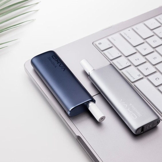 OXVA SlimStick Pod Mod mavi ve gümüş renk, laptop üzerinde.
